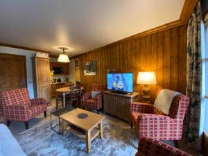 a living room with a couch and chairs and a tv at Petite Marmotte Spacieux Studio pour 4, Skis aux pieds, Le Refuge du Montagnard, Arc 1950 in Arc 1950