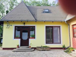 a small yellow and white house with a door at Erika Apartman in Balatonberény +4 photos