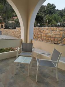 a patio with two chairs and tables and a stone wall at Villa Bianca in Chia