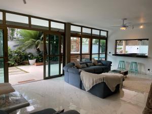 a living room with a blue couch and windows at Vila linda com SPA e Piscina a 50 metros da Praia in Guarujá