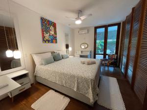 a bedroom with a bed and a large window at Vila linda com SPA e Piscina a 50 metros da Praia in Guarujá +27 photos