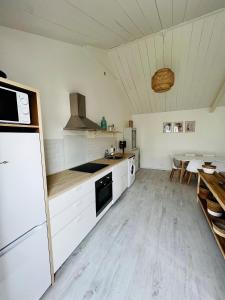 eine große Küche mit weißen Schränken und einem Tisch in der Unterkunft Parenthèse insulaire in LʼÉpine