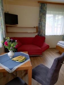 a living room with a red couch and a table with bananas at Pension Strauss in Sankt Lorenzen ob Murau