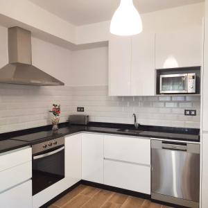 a kitchen with white cabinets and stainless steel appliances at Apartamentos Mar de Nanín in Sanxenxo