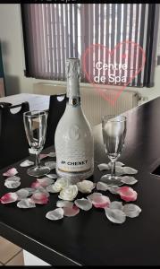 een fles wijn en twee glazen op een tafel met bloemen bij Résidence Gabrielle centre de Spa in Spa
