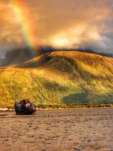 a boat in the water with a rainbow in the background at Barra's Loft in Fort William