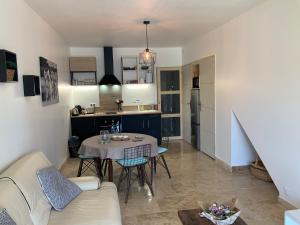 ein Wohnzimmer mit einem Tisch und einer Küche in der Unterkunft Le petit Versailles in Arles