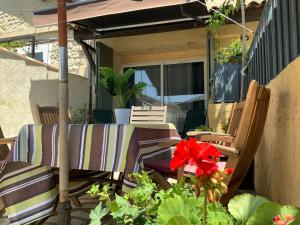 eine Terrasse mit Stühlen und Blumen auf einer Veranda in der Unterkunft Le petit Versailles in Arles