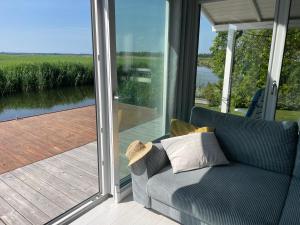 un sofá sentado en un porche junto a una puerta corredera de cristal en Baltic Waterfront Yacht House en Świnoujście