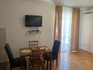a room with a table and chairs and a television on the wall at Apartment Dunja in Boreti