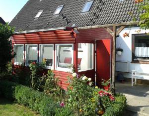 a red house with a red door and some flowers at Windrose - 95102 in Eckernförde