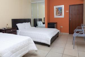 a hotel room with two beds and a chair at Red Sunset Beach Club in Boqueron