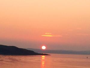 un tramonto sull'acqua con il sole nel cielo di Broom Lodge a Largs