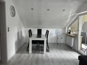 une salle à manger avec une table, des chaises et une horloge dans l'établissement Schwarzwald Appartement Steffanie, à Freudenstadt