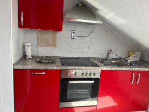 uma cozinha com armários vermelhos e um lavatório em Schwarzwald Appartement Steffanie em Freudenstadt