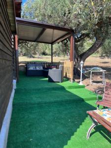 un patio cubierto con una mesa de picnic y un banco en All’Ulivo saraceno, en Trabia