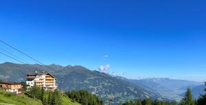 ein Gebäude auf einem Hügel mit Bergen im Hintergrund in der Unterkunft Berghotel Gerlosstein in Hainzenberg