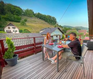un homme et une femme assis à une table sur un pont dans l'établissement Gîte du Silberwald charmant gîte avec spa - jacuzzi , accès privatif, à Stosswihr