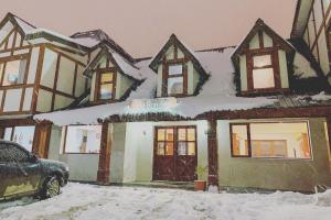 a house covered in snow with a car parked in front at OIKOS in Ushuaia