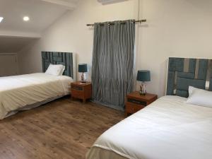 a bedroom with two beds and two night stands with lamps at Villa Populo in Ponta Delgada