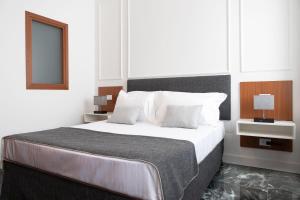 a white bedroom with a large bed with white pillows at Domus Prestige -Suite Repubblica- In Central Rome in Rome