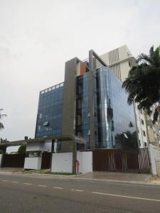 a tall glass building with a palm tree in front of it at Luxury 1 BDR Apartment with Separate BDR, Pool, Gym, Rooftop Pergola - Airport Residential in Accra