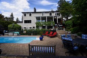 a house with a swimming pool with chairs and a house at A Touch of English B&B in Kelowna