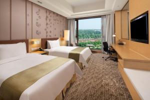 a hotel room with two beds and a flat screen tv at Holiday Inn Nanyang by IHG in Nanyang