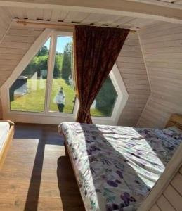 a bed in a room with a large window at Sodyba Anykščių raj. in Anykščiai