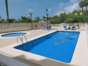 a swimming pool with blue chairs next to a pool at EL DESCANSO in Calpe