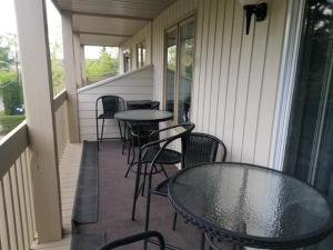 d'un balcon avec des tables et des chaises sur une terrasse couverte. dans l'établissement Superbe condo bord de l'eau à Magog, à Magog