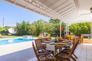 a patio with a table and chairs next to a pool at Villa Stafili by Villa Plus in Litherés