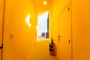 un couloir avec des murs jaunes et une plante en pot dans l'établissement Luxury Penthouse & Terrace - Mons City Center, à Mons