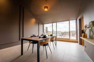 une salle à manger avec une table, des chaises et une grande fenêtre dans l'établissement Luxury Penthouse & Terrace - Mons City Center, à Mons