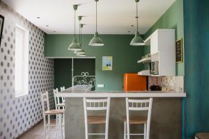 a kitchen with green walls and a counter with stools at Hostel Bongo in Belgrade