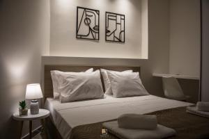 een slaapkamer met een bed met witte lakens en kussens bij Uni Island - Old Town Suites in Heraklion