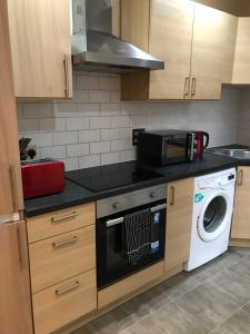 a kitchen with a washing machine and a microwave at Apex Fox Street Apartment with Free Parking in Glasgow