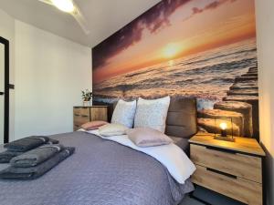 1 dormitorio con 1 cama grande y una pintura en la pared en Apartament el sol, en Gąski