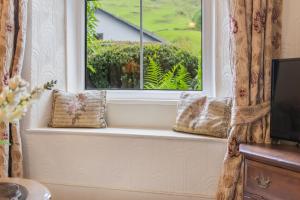 a window with two pillows sitting on a window sill at Sunnywood Cottage in Staveley