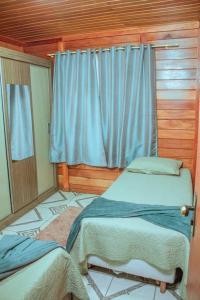 a bedroom with two beds and a window with blue curtains at Chácara em Marechal Floriano in Marechal Floriano