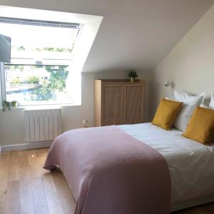 um quarto com uma cama com almofadas amarelas e uma janela em "La Sodilie" charmante maison de ville em Nantes