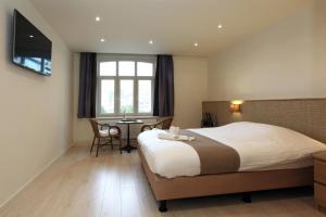 una camera d'albergo con un grande letto e una scrivania di Hotel Cecil a De Panne