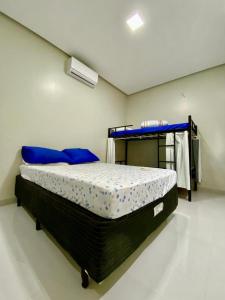 a bedroom with a bed with blue pillows at Hostel Flor de Carajás in Parauapebas