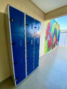 a row of blue lockers in a room with a mural at Hostel Flor de Carajás in Parauapebas