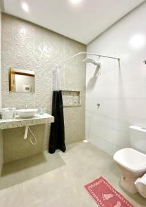 y baño con aseo, lavabo y ducha. en Hostel Flor de Carajás en Parauapebas