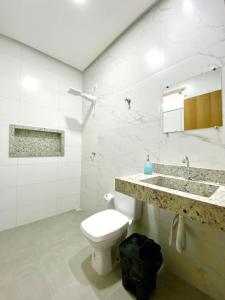 a white bathroom with a toilet and a sink at Hostel Flor de Carajás in Parauapebas