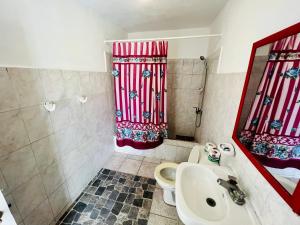 a bathroom with a sink and a red shower curtain at Villa Antonia 16 in Sosúa