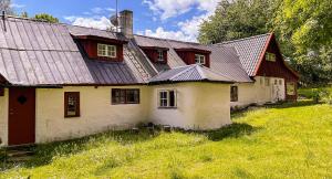 uma casa velha com um telhado de estanho num campo em Tobishirdgård em Simrishamn