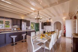 a kitchen and dining room with a white table and chairs at Villa Caribia by Villa Plus in Ágios Stéfanos