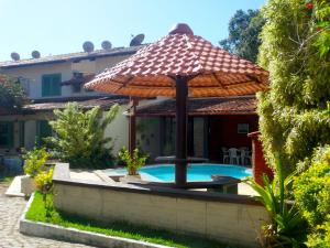 una piscina con sombrilla junto a una casa en VIVA BUZIOS no Condominio Aqua Marina casa13 en Búzios